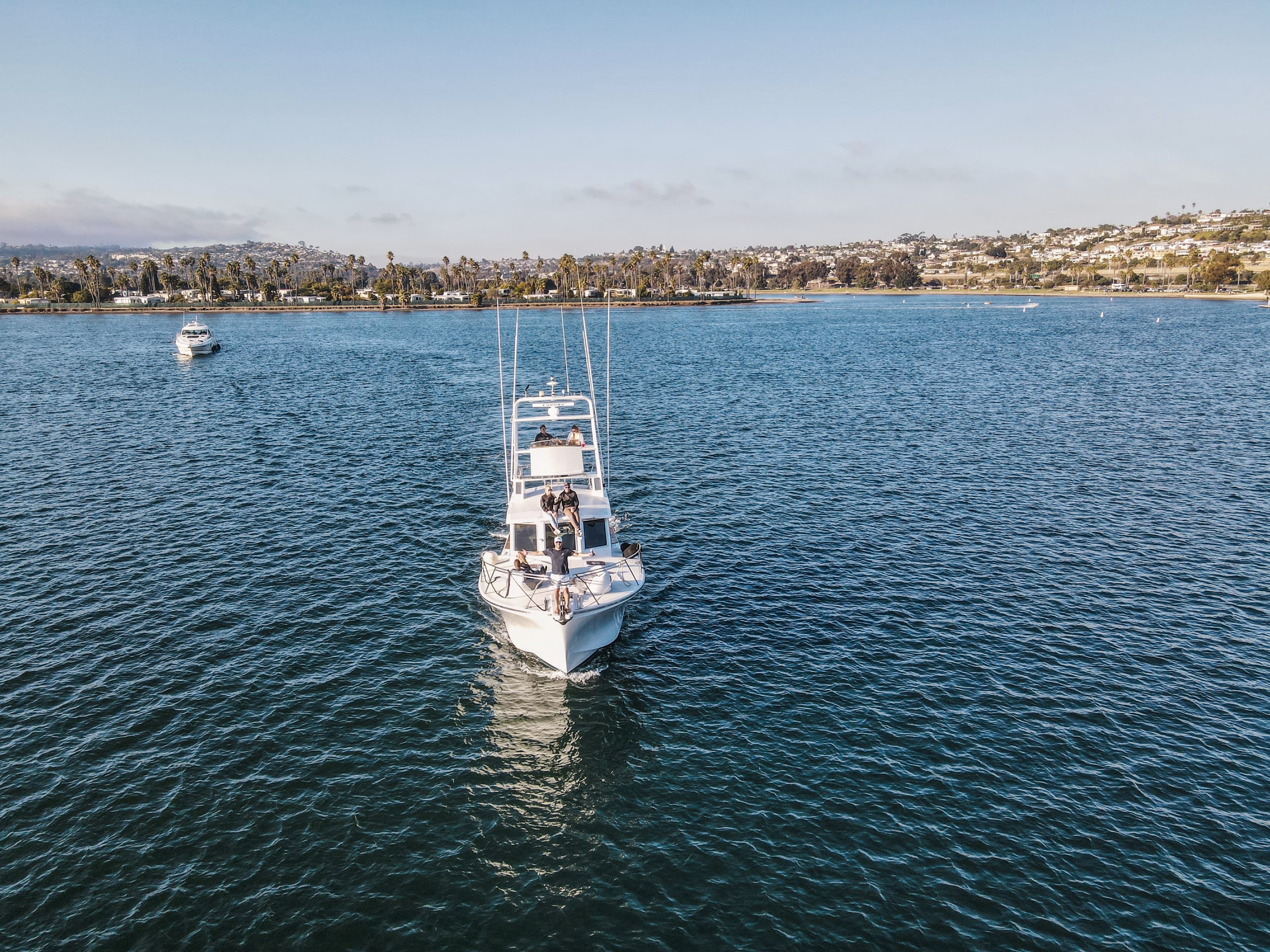 Bow-on aerial view of Bluebill underway across Mission Bay with guests on the flybridge and bow